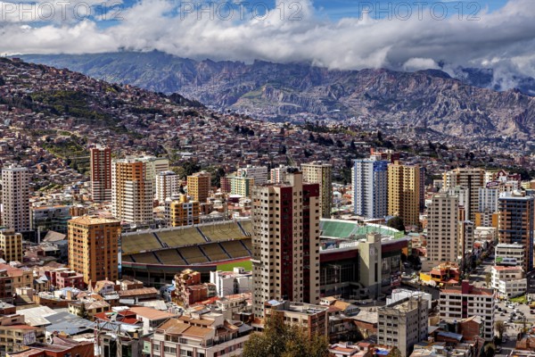 Panorama of La Paz with a view of skyscrapers and a stadium against a mountain backdrop, The houses and skyscrapers of the city centre of La Paz in Bolivia