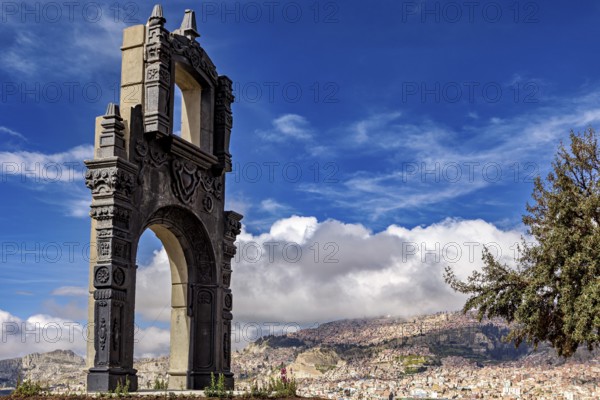 A stone gate with ornate decorations in front of a sprawling cityscape and a blue sky, The gate at the Killi Killi viewpoint in La Paz, Bolivia