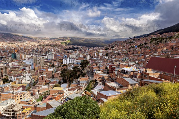 Hilly cityscape of La Paz with red roofs and cloudy skies, The houses and skyscrapers of the city centre of La Paz in Bolivia