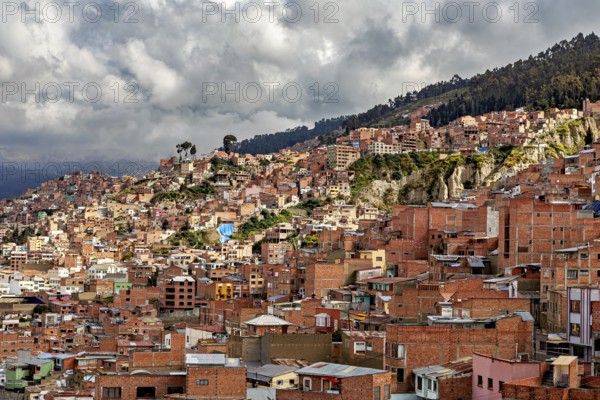 Houses spread across the hilly landscape of La Paz under a cloudy sky, The houses and skyscrapers of the city centre of La Paz in Bolivia
