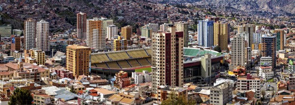 Urban scenery with stadium and skyscrapers in front of mountains, The houses and skyscrapers of the city centre of La Paz in Bolivia