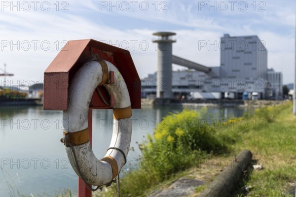 Lifebuoy in the foreground with industrial backdrop on a sunny day, at the harbour of Linz Upper Austria Austria