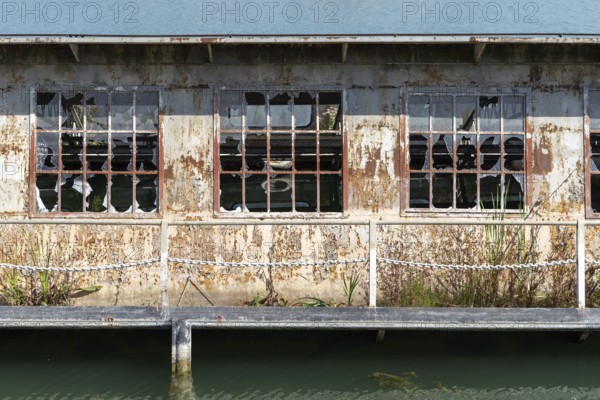 Abandoned building with broken windows and rust next to a body of water, at the harbour of Linz Upper Austria Austria