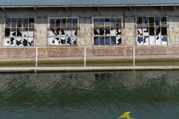 Dilapidated building with broken windows and rusty structures on the waterfront, at Linz harbour Upper Austria Austria