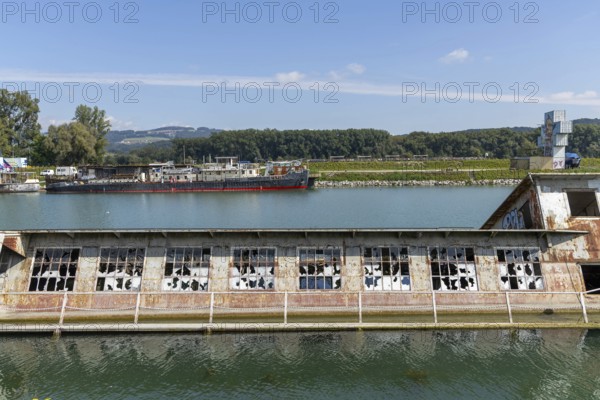 Ruins of an industrial building in the water with a ship in the background, at the harbour of Linz Upper Austria Austria