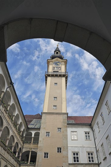 View through an arch onto a historic clock tower with blue sky, Arkardenhof Landhaus Linz Upper Austria Austria