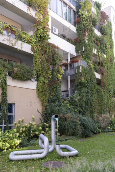 Modern façade with lush greenery and a sculpture in the front garden, Linz city centre Upper Austria Austria