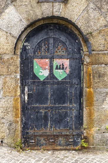 Old door with coat of arms on a stone wall, surrounded by rust and weathering, Pöstlingsbergkirche pilgrimage basilica Sieben Schmerzen Maria Linz Upper Austria Austria