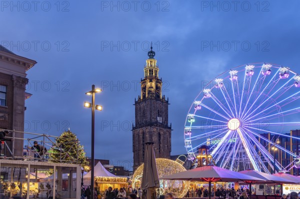 Ferris wheel on the Grote Markt at Christmas time and the Martinitoren or Martini tower of the Martinikerk or Martini church at dusk, Groningen, Netherlands