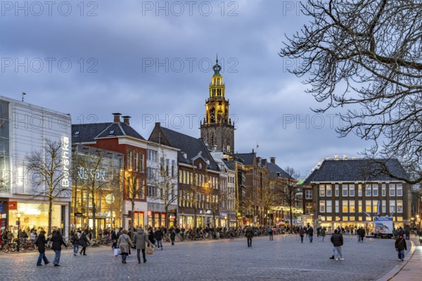 Shops at the fish market Vismarkt and the church tower Martinitoren or Martinitower of the Martinikerk or Martinikirche at dusk, Groningen, Netherlands