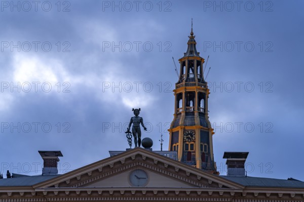 Statue of the god Mercury on the roof of the Korenbeurs former grain exchange and the steeple of the Aa church at dusk, Groningen, Netherlands