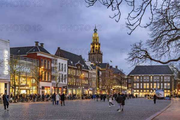 Shops at the fish market Vismarkt and the church tower Martinitoren or Martinitower of the Martinikerk or Martinikirche at dusk, Groningen, Netherlands
