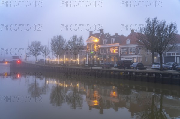 Typical canal in the foggy evening twilight, Harlingen, Friesland, Netherlands