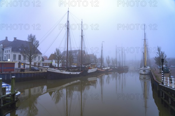 Typical canal with sailing boats in the winter fog, Harlingen, Friesland, Netherlands