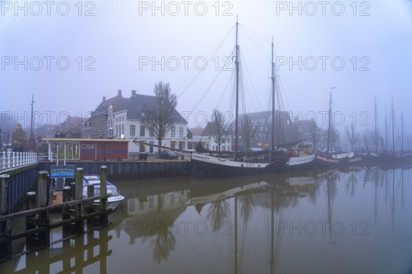 Typical canal with sailing boats in the winter fog, Harlingen, Friesland, Netherlands