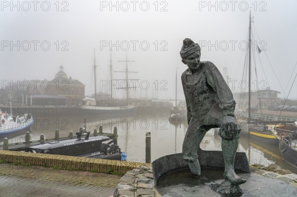 Sculpture The Tobbedanser in the foggy harbour of Harlingen, Friesland, Netherlands