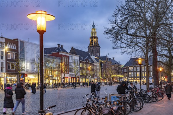 Shops at the fish market Vismarkt and the church tower Martinitoren or Martinitower of the Martinikerk or Martinikirche at dusk, Groningen, Netherlands