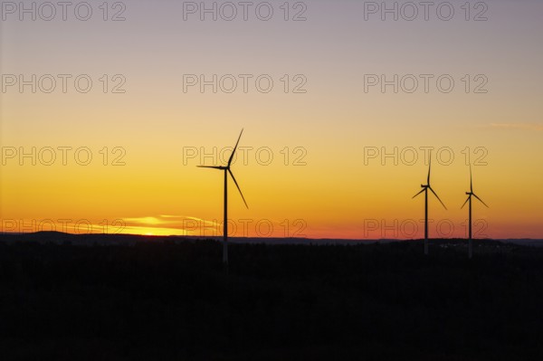 Wind turbines in front of a calm, golden sunset, near Schorndorf im Remstal, Baden-Württemberg, Germany