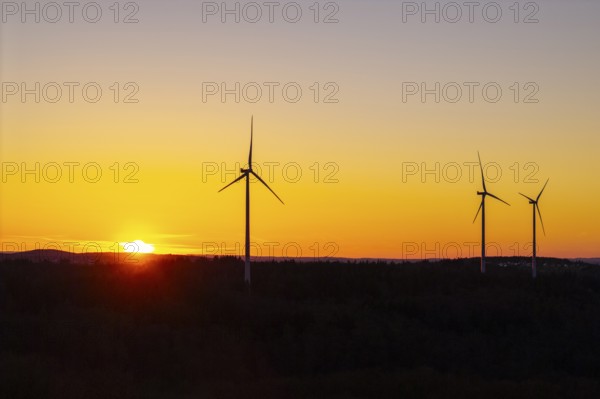 Three wind turbines in front of an orange-coloured sunset, near Schorndorf im Remstal, Baden-Württemberg, Germany