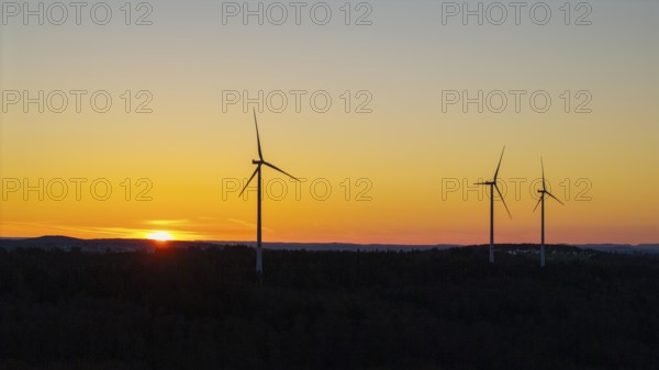 Wind turbines at dusk with an orange sky in the background, near Schorndorf im Remstal, Baden-Württemberg, Germany