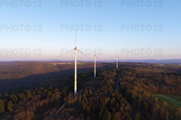 A wind farm spreads out over a wooded area under a clear sky, near Schorndorf in the Rems Valley, Baden-Württemberg, Germany