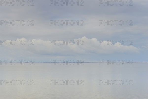 North Sea coast, special light mood over the Wadden Sea with rising water and calm wind, on the horizon the island of Juist, Norddeich, Lower Saxony, Germany