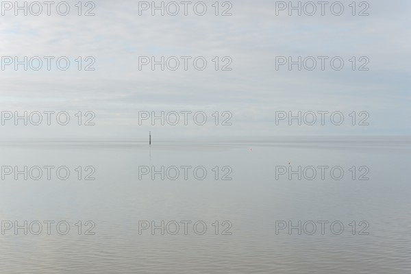North Sea coast, special light atmosphere over the Wadden Sea with rising water and calm wind, navigation sign danger spot, Norddeich, Lower Saxony, Germany