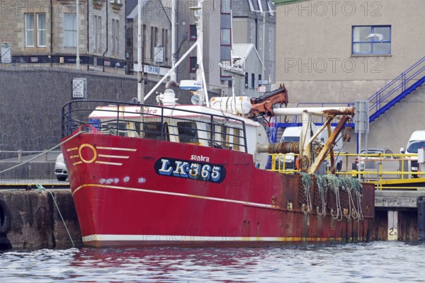 Red fishing boat in harbour against urban background with ropes on board, Lerwick, Shetland Islands, Scotland, Great Britain