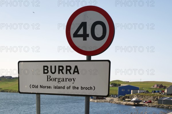 A road sign on an island with a clear blue sky and a body of water in the background, reference to the old Norwegian spelling, Shetland Islands, Scotland, Great Britain