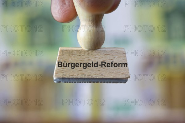 (Photomontage) Stamp with the inscription BÜRGERGELD in front of blurred euro banknotes in the background
