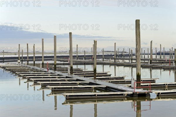 Winter day on the North Sea coast, reflection of boat moorings in the marina, Norddeich, Lower Saxony, Germany