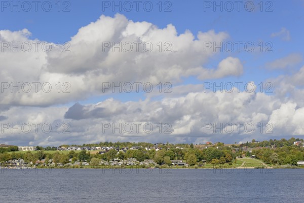 View over the Möhnesee, Körbecke village with the lake park and the lakeside promenade, blue cloudy sky, Möhnetalsperre, North Rhine-Westphalia, Germany