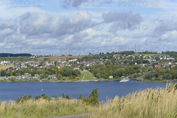 View over the Möhnesee, Körbecke village with the lake park and the lakeside promenade, blue cloudy sky, Möhnetalsperre, North Rhine-Westphalia, Germany