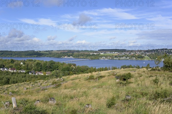 View over the Möhnesee, Körbecke village with the lake park and the lakeside promenade, blue cloudy sky, Möhnetalsperre, North Rhine-Westphalia, Germany