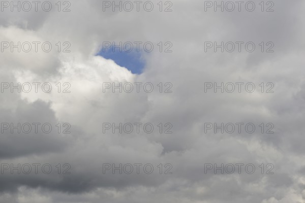 Cloud formation, blue sky shines through a gap in the closed cloud cover, North Rhine-Westphalia, Germany