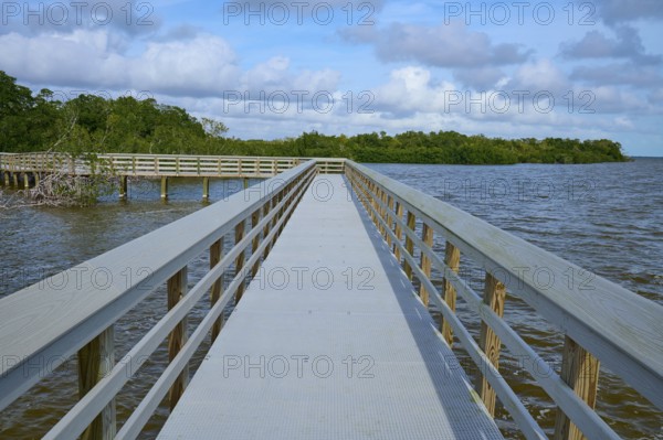 A long wooden walkway leads into the water, under a cloudy sky, West Lake View Point, Everglades National Park, Florida, USA