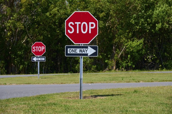 Stop signs and one-way street signs in front of a green tree landscape, Flamingo, Everglades National Park, Florida, USA