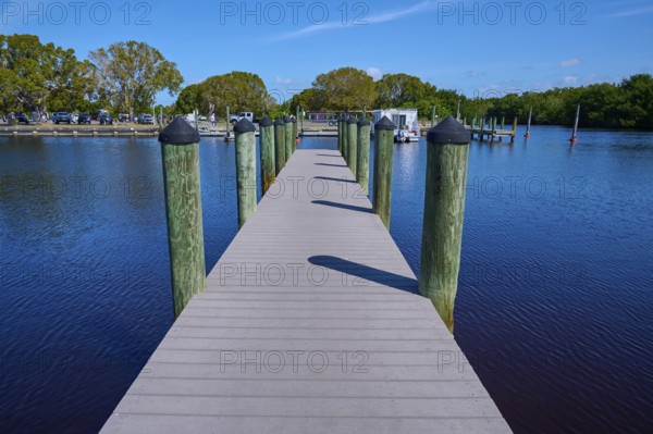 Wooden walkway leads over calm water to a boat dock, Flamingo, Marina, Everglades National Park, Florida, USA