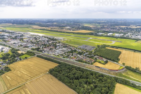Aerial view, Dortmund Airport, residential area and commercial area Chaussee with noise protection wall on the B1 federal road, Obermassener Heide, Holzwickede, Ruhr area, North Rhine-Westphalia, Germany, DE, Europe, flight emission, airport, aircraft noise, airfield, commercial enterprises, commercial area, commercial area, commercial location, commercial use, property tax, real estate, industrial area, runway, aerial view, aerial photography, aerial photography, runway, overview, bird's-eye view, residential area, residential area, residential buildings, residential quality, residential neighbourhood, housing estate, birds-eyes view, overview