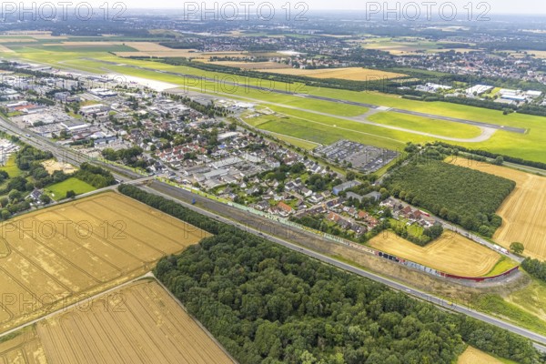 Aerial view, Dortmund Airport, residential area and commercial area Chaussee with noise protection wall on the B1 federal road, Obermassener Heide, Holzwickede, Ruhr area, North Rhine-Westphalia, Germany, DE, Europe, flight emission, airport, aircraft noise, airfield, commercial enterprises, commercial area, commercial area, commercial location, commercial use, property tax, real estate, industrial area, runway, aerial view, aerial photography, aerial photography, runway, overview, bird's-eye view, residential area, residential area, residential buildings, residential quality, residential neighbourhood, housing estate, birds-eyes view, overview
