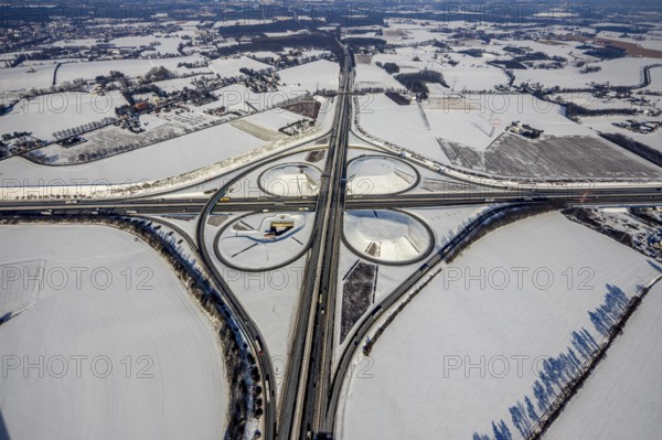 Aerial view, Kamen junction in winter, A1 and A2, helicopter sculpture Yellow Angel, Kamen, Ruhr area, North Rhine-Westphalia, Germany, motorway A1, motorway A2, motorway junction, DE, Europe, cloverleaf shape, aerial view, aerial photography, aerial photography, snow, sculpture, overview, bird's eye view, winter, birds-eyes view, overview