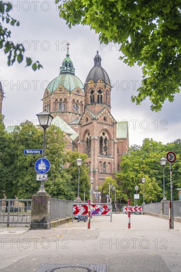 Impressive church with twin towers surrounded by trees on a cloudy day, Munich, Germany