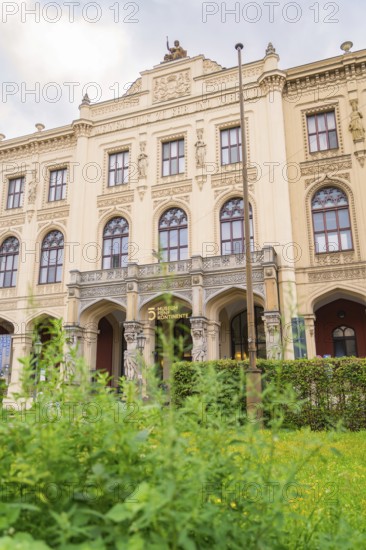 A magnificent historic building with ornate facades surrounded by lush green plants, Munich, Germany