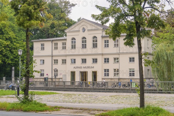 Front view of the Alpine Museum, framed by trees. A classic building in an urban environment, Munich, Germany