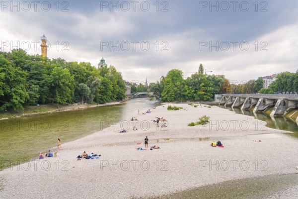 River landscape with island and bridge, surrounded by trees. People enjoying their free time on the riverbank, Munich, Germany
