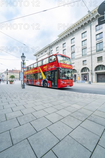 A red double-decker bus for city tours in front of historic buildings in Munich, Munich, Germany