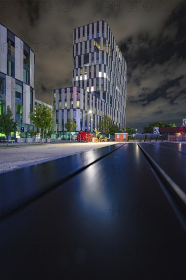 Modern building at night with strong lighting and cloudy sky, urban and stylish, Munich, Germany