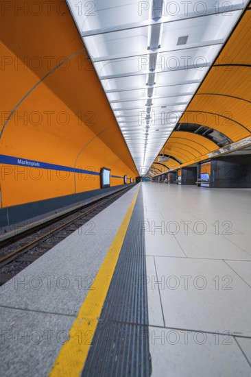 Orange-coloured symmetrical underground station with modern lighting and clear lines, Munich, Germany