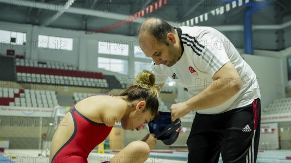 A coach assists a female swimmer with limb loss in adjusting her swim cap before training in an indoor swimming pool, Gaziantep, Gaziantep, Türkiye