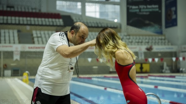 A female Paralympic swimmer with amputated arms performs warm-up exercises on a mat before entering the swimming pool for training, Gaziantep, Gaziantep, Türkiye